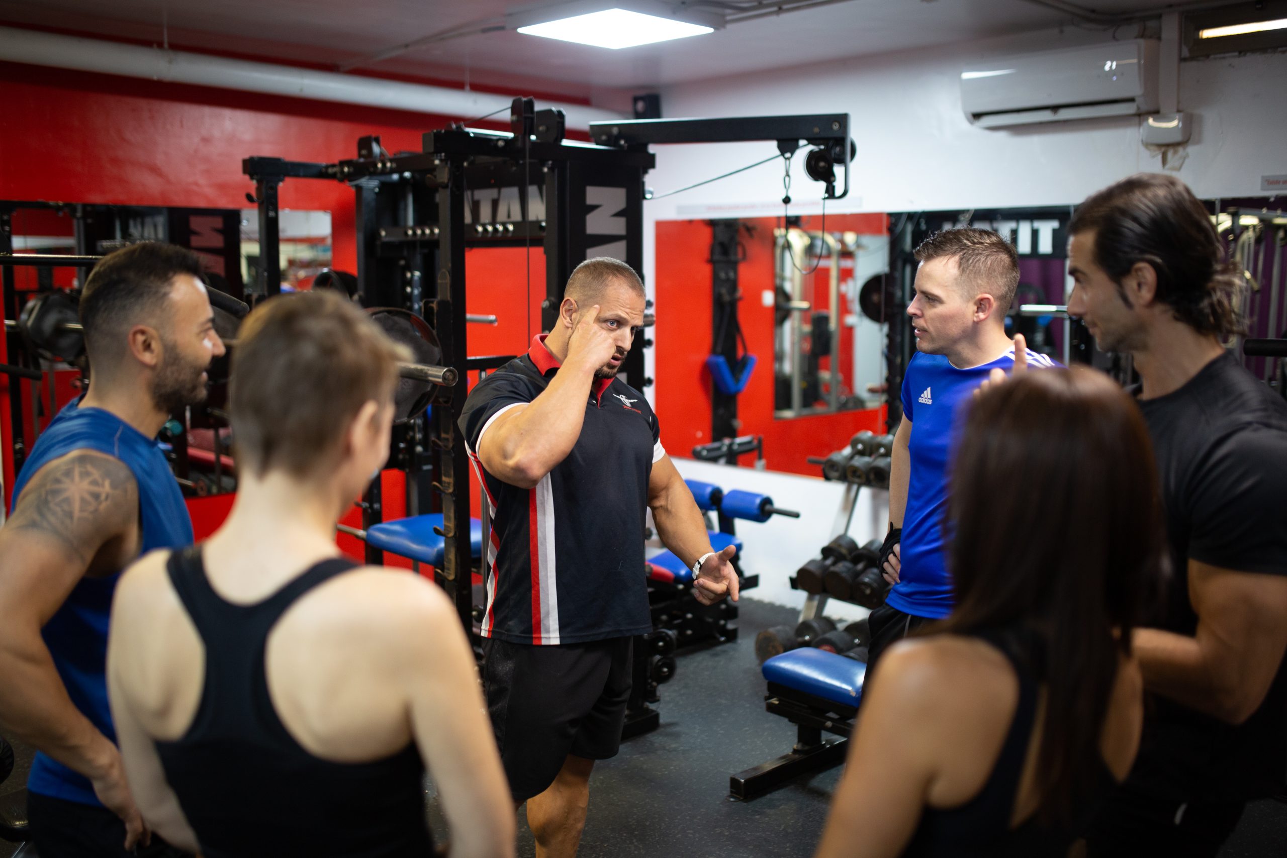 Entrenador personal Bernat Scorus explicando técnicas de entrenamiento a un grupo reducido en un gimnasio privado en Alicante.